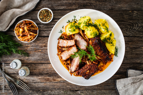 Tasty roast ribs with boiled potatoes on wooden table

