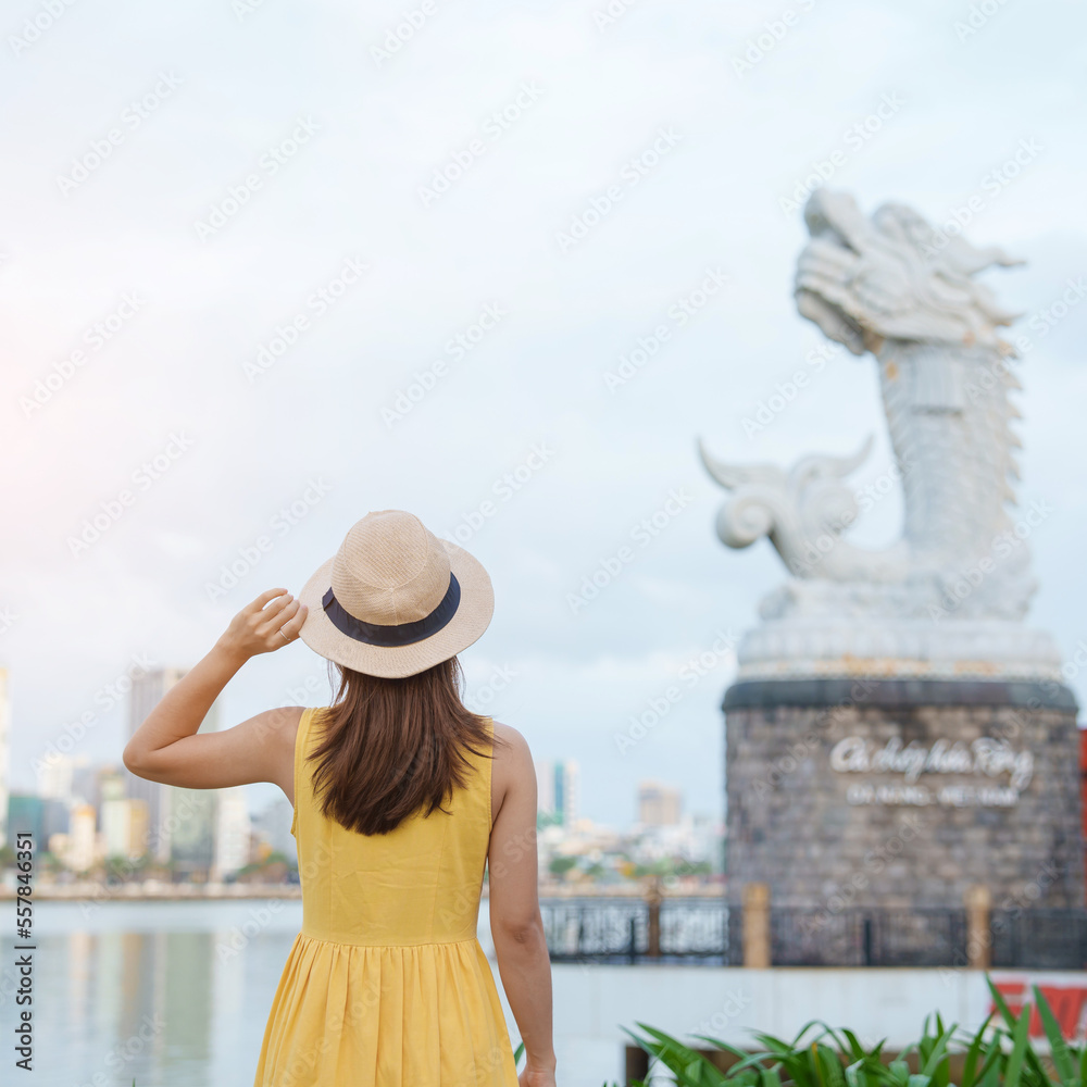 Fototapeta premium Woman Traveler with yellow dress visiting in Da Nang. Tourist sightseeing the river view with Carp Dragon Statue or Ca Chep Hoa Rong.Landmark and popular. Vietnam and Southeast Asia travel concept