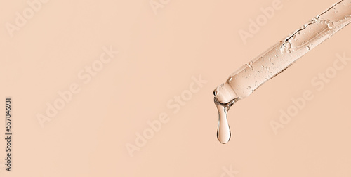 Wall Mural serum pipette close-up with falling drop on a beige background