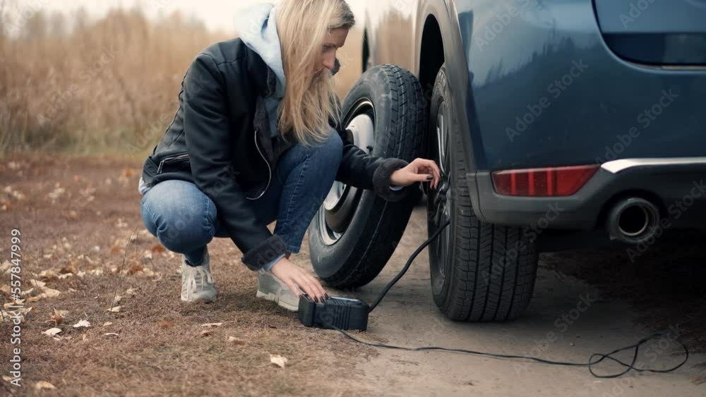 woman using electric tire inflator for pumping flat tire .