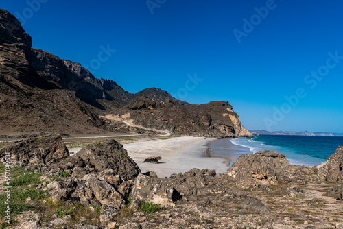 Oman, Dhofar, Salalah, Fazayah Beach with coastal rocks in foreground photo