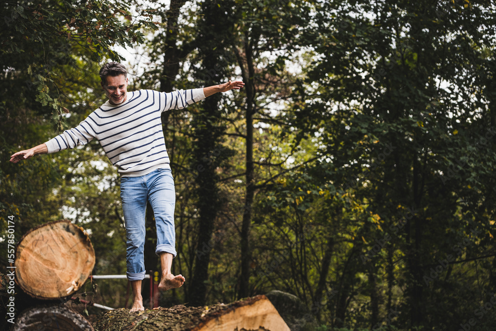 Cheerful mature man walking on log in forest Cheerful mature man walking on log in forest