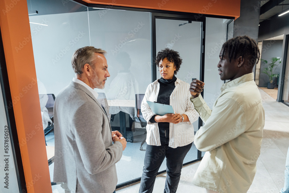 Young businessman having discussion with colleagues standing in office