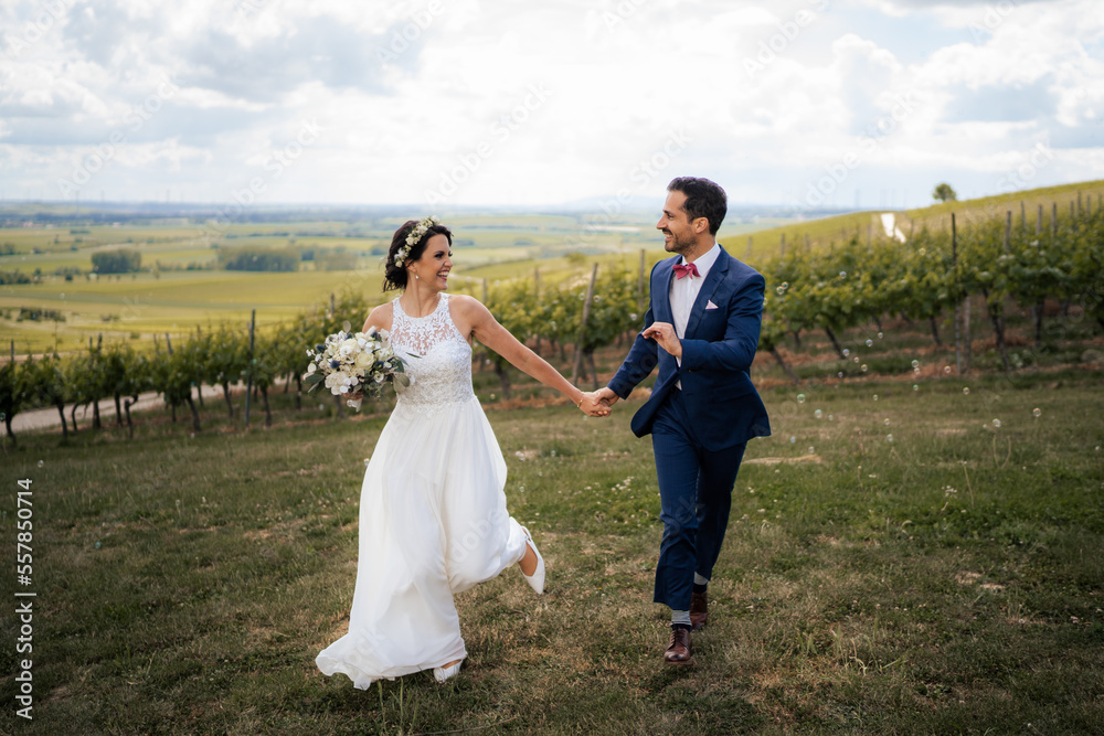 Wedding couple, groom is running while holding brides hand in black and white in the vineyards of Rheinhessen	