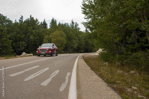 2023 Route. Road in the forest ith red car.