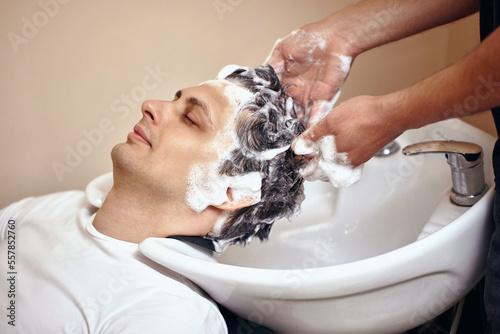 Barber washing hair of caucasian man , close-up