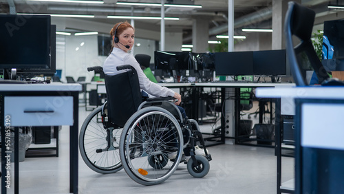 Caucasian woman moves around the office in a wheelchair. Female call center worker.