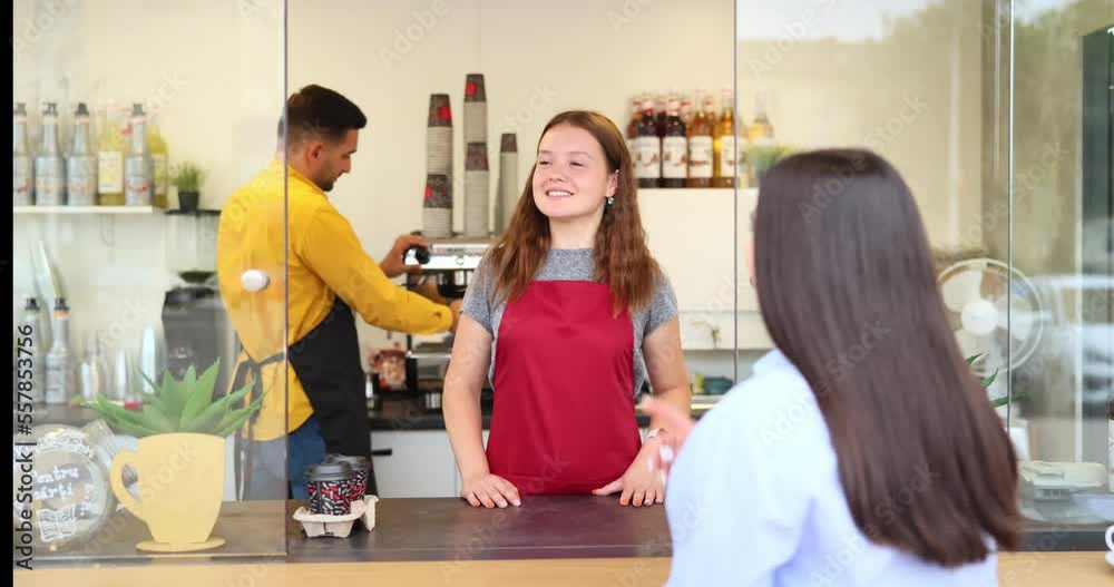 Waitress taking order from client at cashier counter in coffee shop. Face with a big smile.