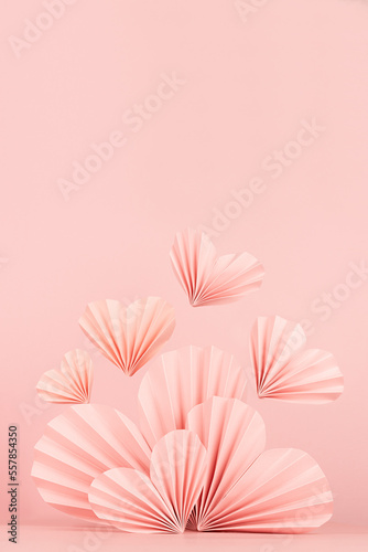 Valentines day scene - pink ribbed paper hearts with flying heart on soft light pink  copy space  vertical. Sweet love mockup for presentation cosmetic product  goods  design  card  poster  flyer.