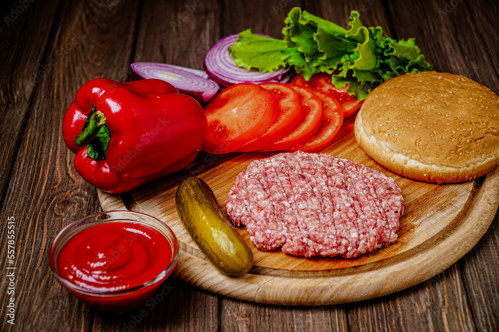 From above view of process of making burger with vegetables, bun and artificial meat on wooden board From above view of process of making burger with vegetables, bun and artificial meat on wooden board