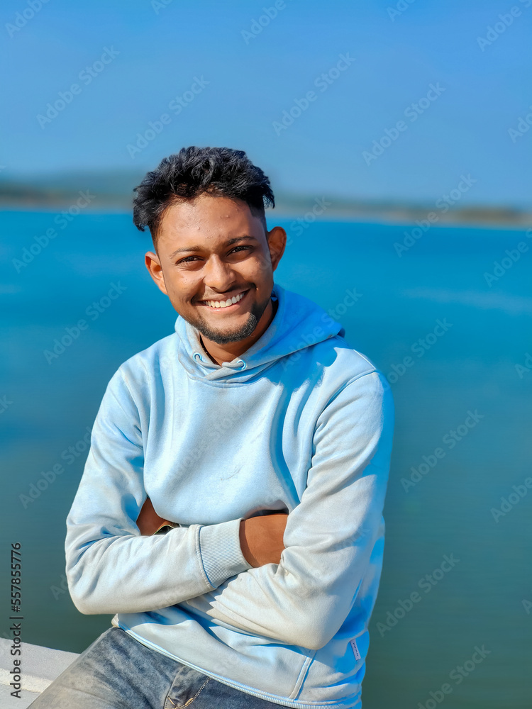 Young boy smiling portrait, blue lake and sky on the background Selective focus