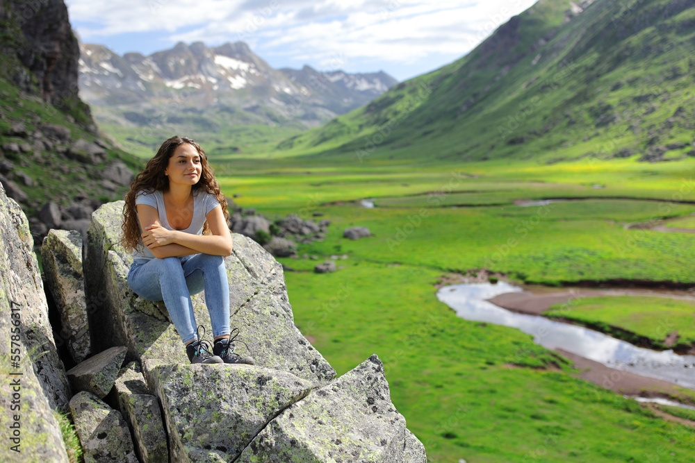 Woman contemplating mountain views in a cliff