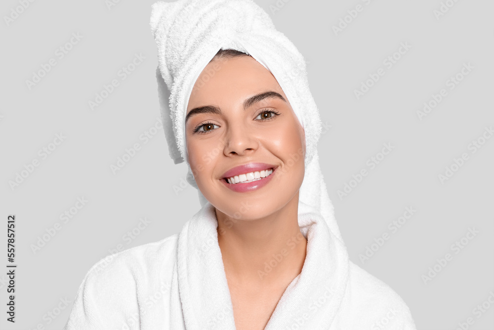 Young woman in bathrobe with towel on light grey background. Spa treatment Young woman in bathrobe with towel on light grey background. Spa treatment