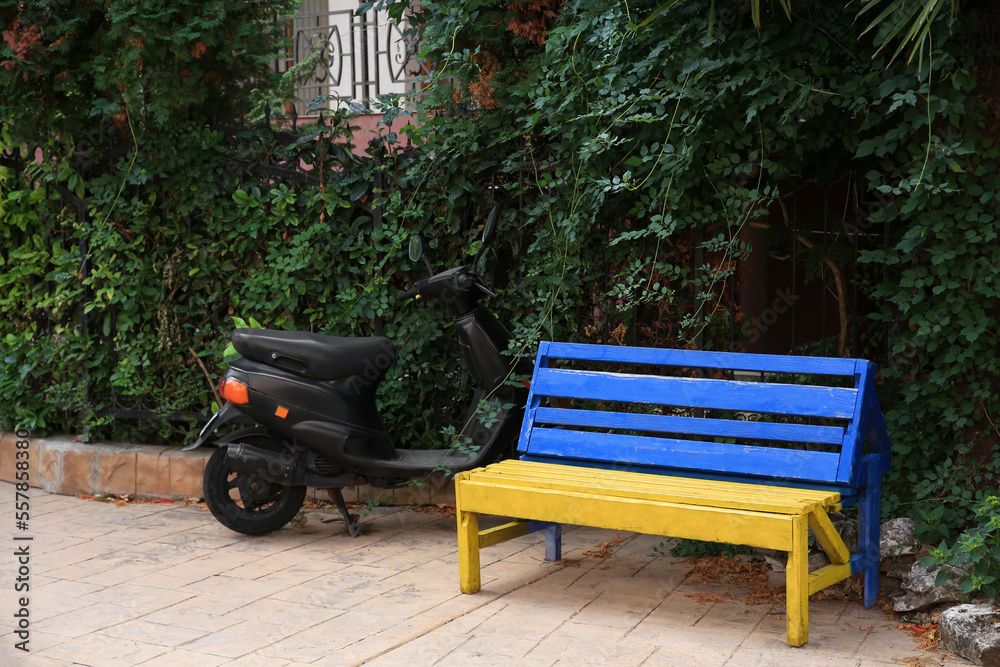 Beautiful blue and yellow wooden bench near scooter outdoors