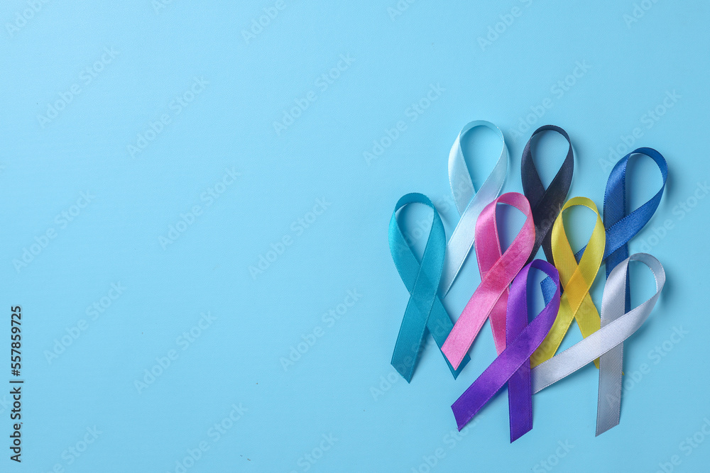 Stack of colorful awareness ribbons on blue background with copy space. World cancer day concept. 