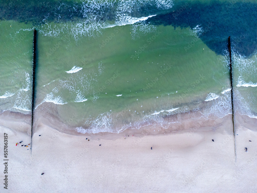 Snowy beach at Baltic sea in winter. Tourism in Poland. Aerial view of nature seashore and walking people.