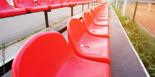 Row with empty red plastic seats on sportive playground outdoor photo