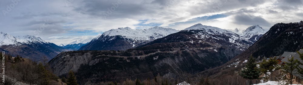  image panoramique avec une vue magnifique sur les montagnes enneigées des Alpes. le soleil éclaire le sommet des montagnes avec un beau ciel bleu et quelques nuages.