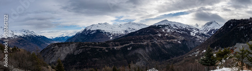  image panoramique avec une vue magnifique sur les montagnes enneigées des Alpes. le soleil éclaire le sommet des montagnes avec un beau ciel bleu et quelques nuages.