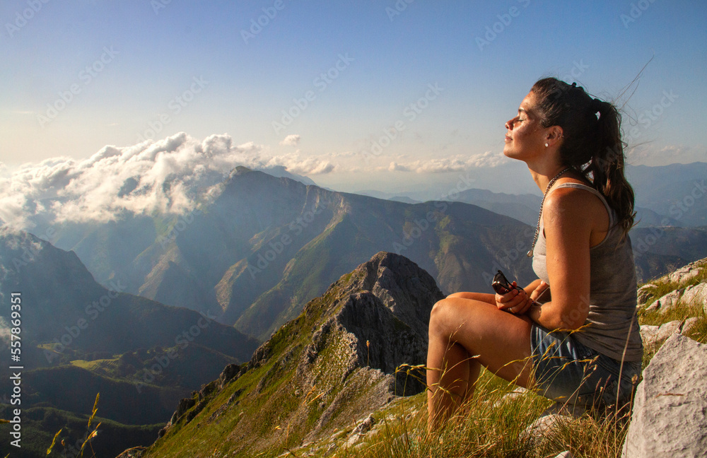 Mujer joven meditando en altas montañas cubiertas de nubes