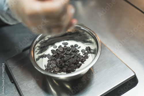 Pastries in making. Person weighing chocolate chips in a meal bowl. High angle shot. High quality photo