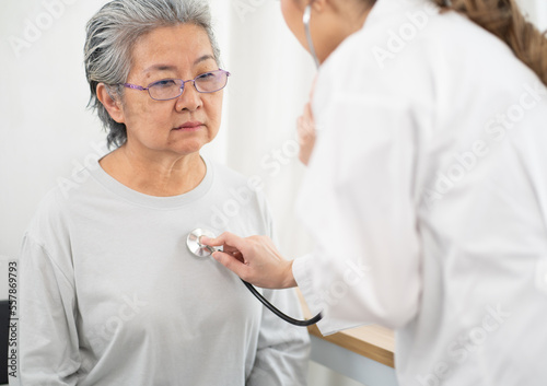 Young female medical doctor examining senior woman patient in hospital. Asian elderly visit professional physician to examine her health. Young nurse friendly talking to sick patient for medicine.