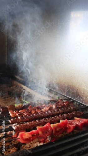 Cooking shish kebab and meat skewers, tomatoes and green peppers on a grill. High quality footage