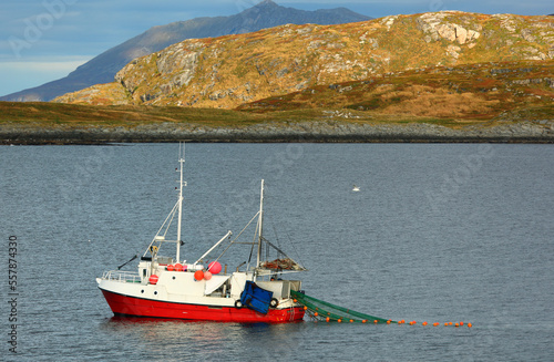 Fishing boat in a fjord with rocky shores in autumn in Norway