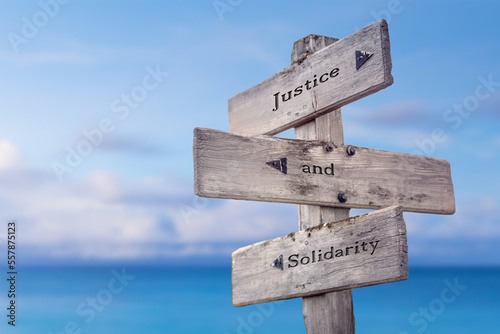justice and solidarity text quote on wooden signpost crossroad by the sea