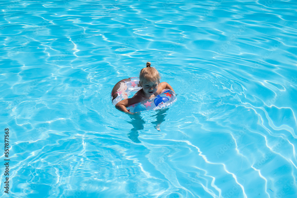 Child girl swims with an inflatable ring in the pool. Top view, flat lay