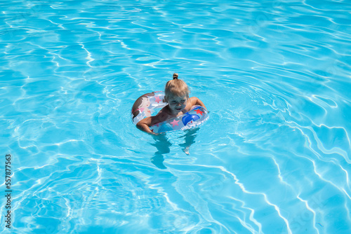 Child girl swims with an inflatable ring in the pool. Top view, flat lay