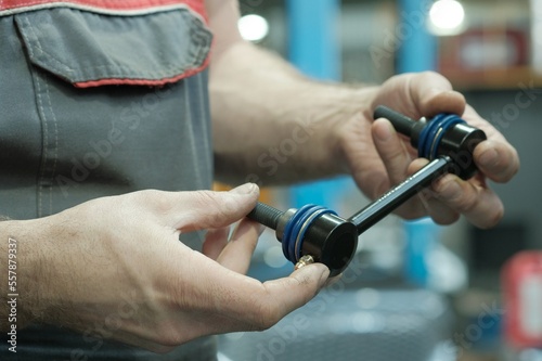 Maintenance of a passenger car. Stabilizer bar of the front suspension of the car. A new part of the suspension system is in the hands of an auto mechanic.