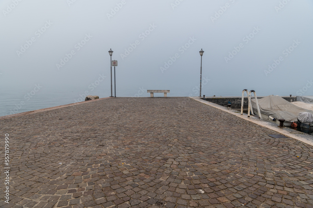Old harbor of the small and picturesque town of Lazise on Lake Garda in the winter season. Lazise, Verona province, northern Italy - January 21, 2022