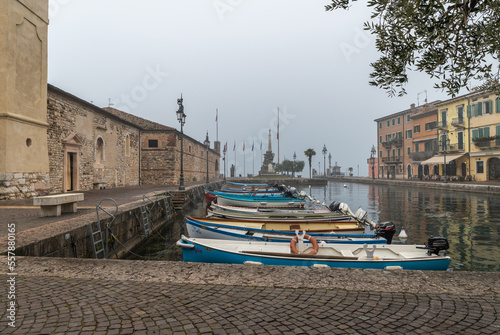 Old harbor of the small and picturesque town of Lazise on Lake Garda in the winter season. Lazise, Verona province, northern Italy - January 21, 2022