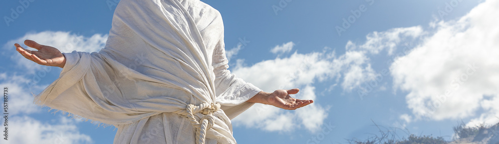 Close up of body of man in white robe with arms open in blessing