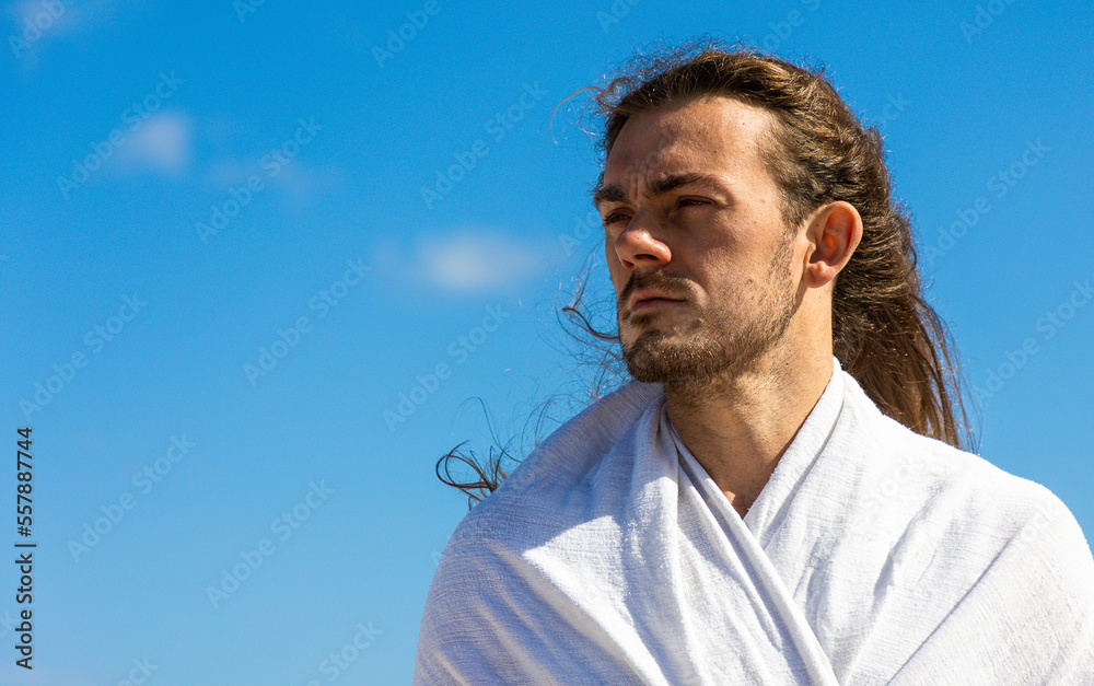 Handsome man who looks like Jesus Christ head shot against blue sky