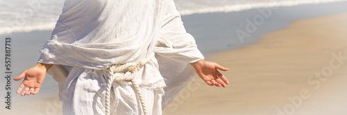 Christ-like man in white robe with open arms, closeup body shot next to sea