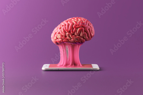 The human brain is stuck to a smartphone on a purple background. Concept of a day without gadgets. photo