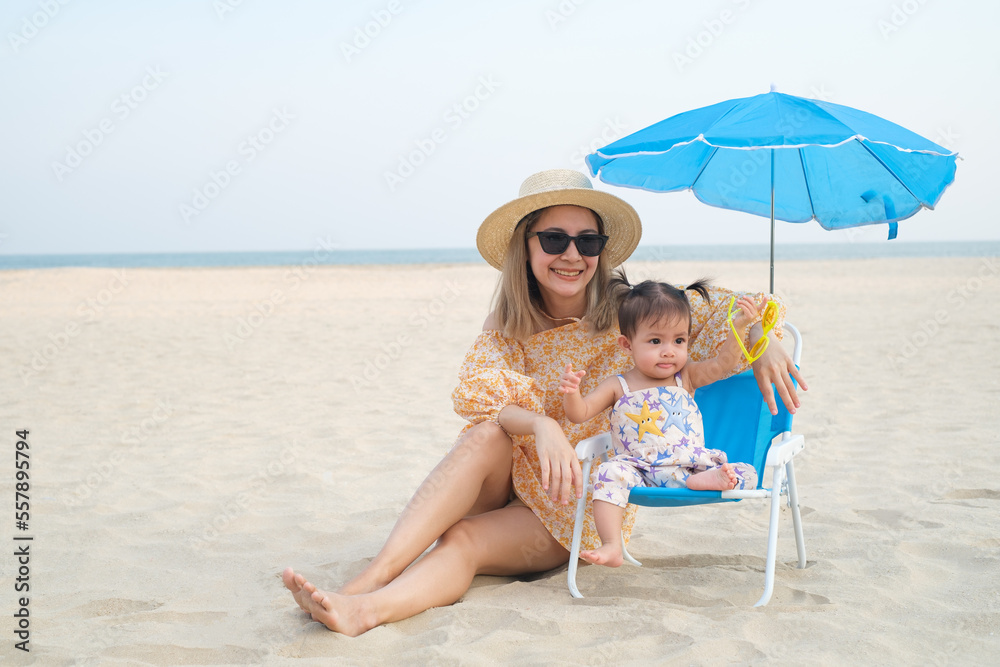 Young lovely mother and her little daughter relax on tropical white sand beach. Travel on summer holiday vacation.