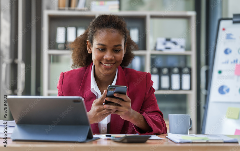 Young african american businesswoman red suit working at desk and using digital tablet in the modern office. Start up SME worker concept. Young african american businesswoman red suit working at desk and using digital tablet in the modern office. Start up SME worker concept.