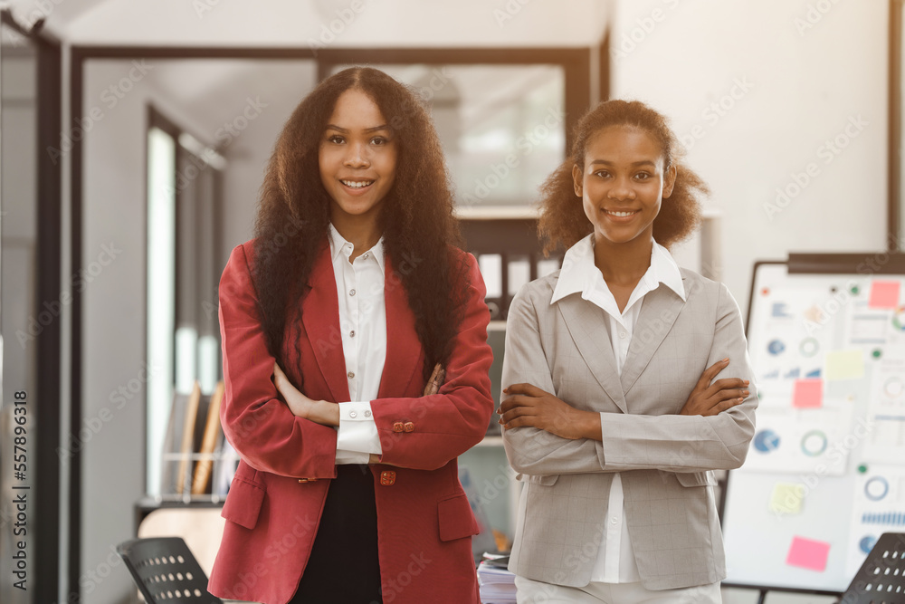 Young diverse african american female coworkers working together on start up project. Business people meeting around a boardroom table discussing creative concept Young diverse african american female coworkers working together on start up project. Business people meeting around a boardroom table discussing creative concept