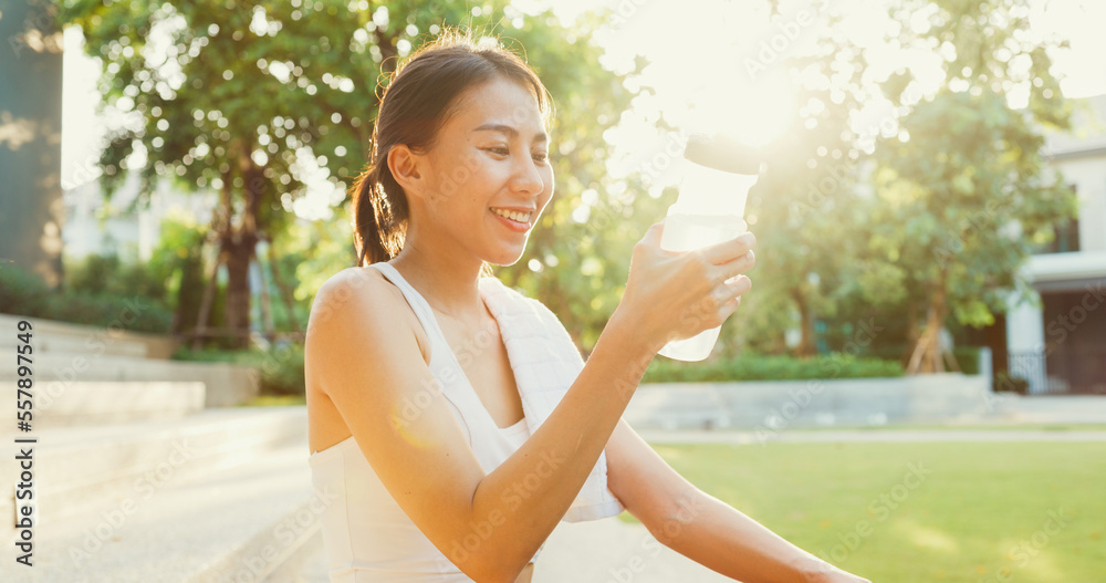Beautiful young Asia athlete lady exercises drinking water because feel tired after running in urban park environment in evening. Outside workout and fitness healthy lifestyle concept. Beautiful young Asia athlete lady exercises drinking water because feel tired after running in urban park environment in evening. Outside workout and fitness healthy lifestyle concept.
