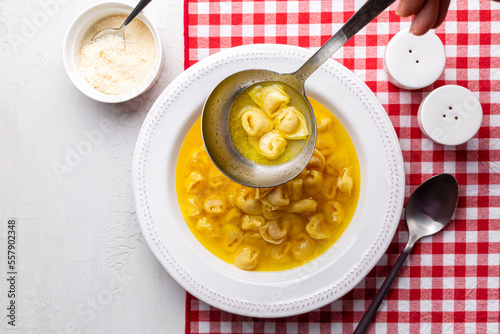 Ladle with tortellini in beef and chicken broth. Serving egg pasta originally from the Italian region of Emilia, Bologna. Stuffed with a mix of meat, prosciutto, mortadella, hard cheese, egg 