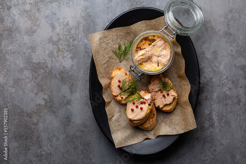 Plate with baguette toast with foie gras pate, directly above. A specialty food product made of the liver of a duck or goose,  in a glass jar. Decorated with red pepper and dill. photo