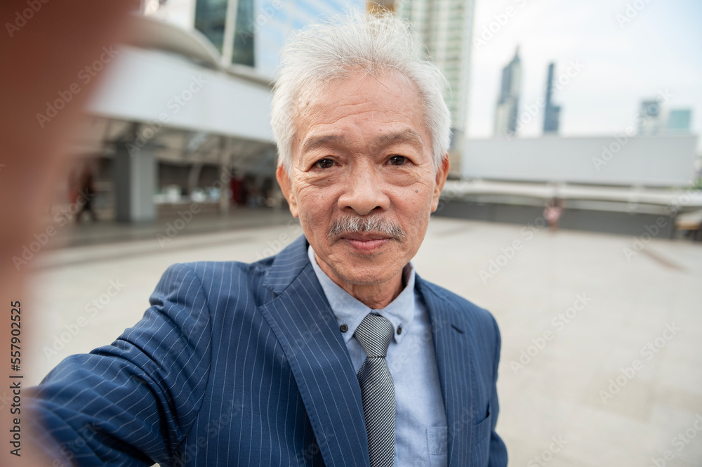 Asian senior mature middle aged businessman making video call in modern city Asian senior mature middle aged businessman making video call in modern city