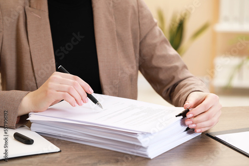 Woman signing documents at table in office, closeup