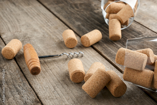 Glasses with wine corks and corkscrew on wooden table