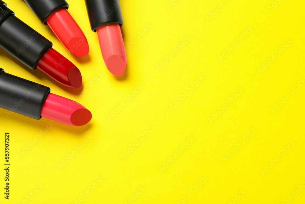 Many bright lipsticks on yellow background, flat lay. Space for text Many bright lipsticks on yellow background, flat lay. Space for text
