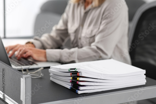 Businesswoman working with laptop at grey table in office  focus on documents. Space for text