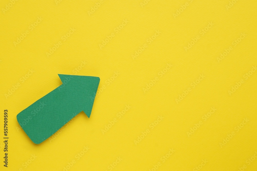 Paper arrow on yellow background, top view. Space for text Paper arrow on yellow background, top view. Space for text